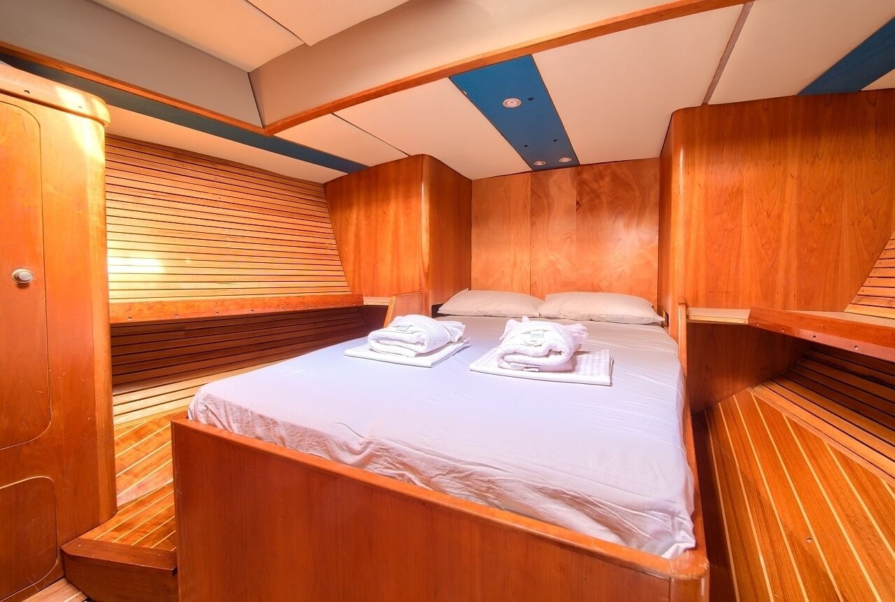 Una cabaña pequeña con una cama individual, paneles de madera y un rincón de descanso.