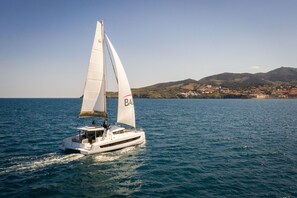 Un voilier à la coque blanche glisse sur l’eau, ses voiles gonflées par le vent.