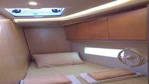 A compact, well-lit cabin with a bed, a fan, and a skylight. - Sun-Kissed Sailing Journey in Trat, Koh Chang (Ko Chang)