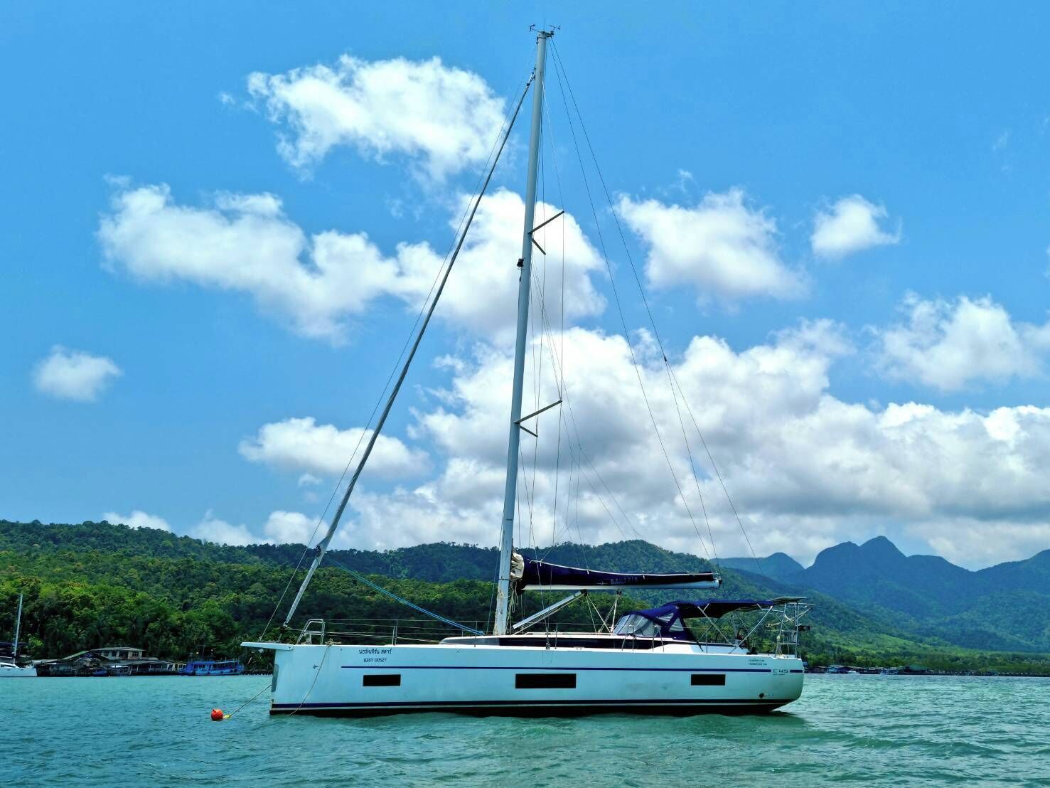 Un velero en aguas tranquilas con montañas al fondo.