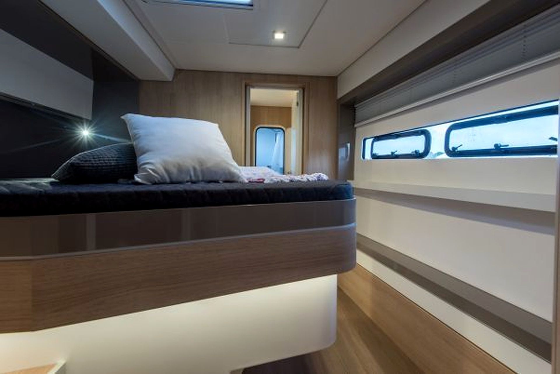 A bunk bed with a headboard, a window with a view, and a door leading to another room.