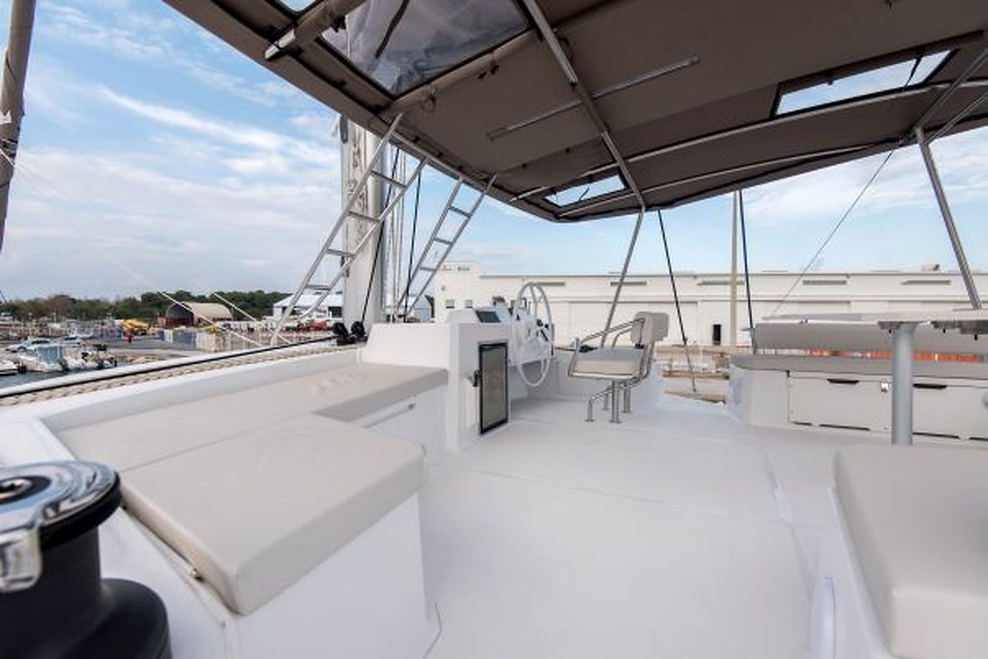 A boat deck with a steering wheel, a cushioned seat, and a table.