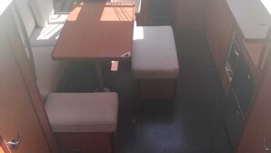 Ein kompaktes Wohnmobil-Interieur mit einer Küchenzeile, einem kleinen Esstisch und einer Bank.