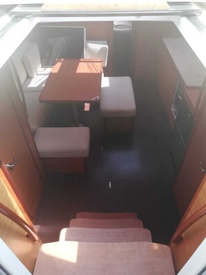 Ein kompaktes Wohnmobil-Interieur mit einer Küchenzeile, einem kleinen Esstisch und einer Bank.