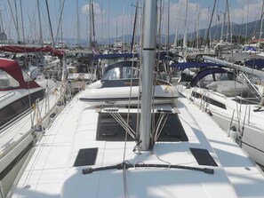 A marina with multiple sailboats docked, featuring a central mast and a covered area.