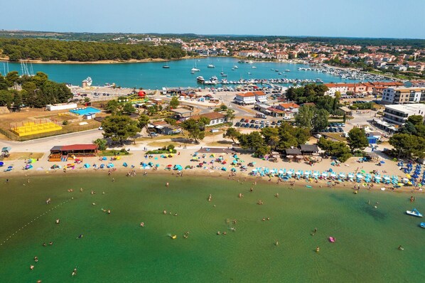 An aerial view of a coastal town with a marina, beach, and various buildings.