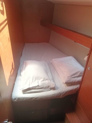 A small, compact room with a single bed, wooden walls, and a simple layout.