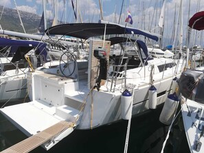 Marina con varios veleros amarrados, destacando una paleta de colores azul y blanco, un cabrestante y una rueda de timón.