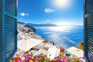 Une vue sur la côte, avec des bâtiments blancs, une mer d'un bleu limpide et un soleil éclatant.