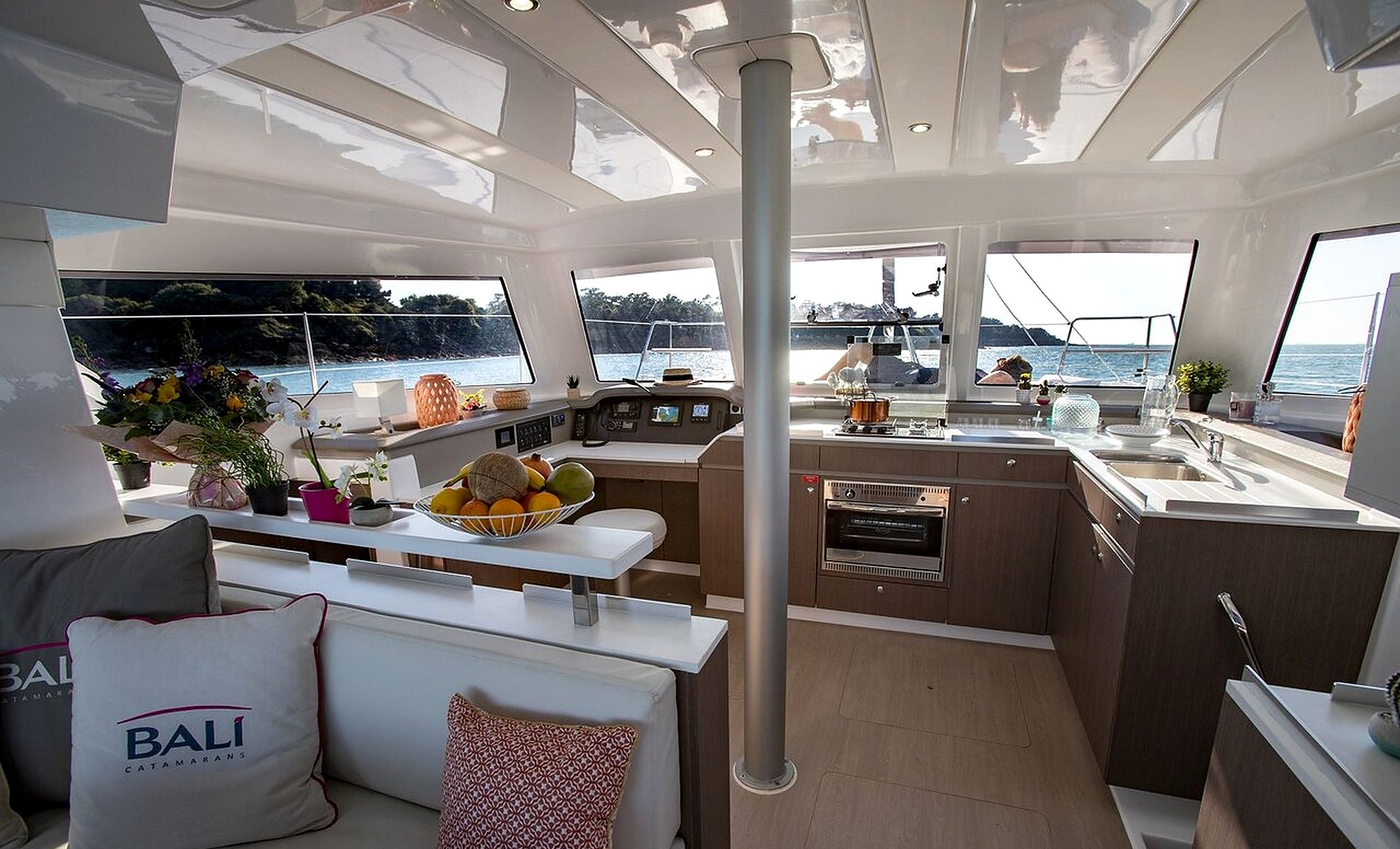 A modern yacht interior with a dining area, kitchen, and seating space.
