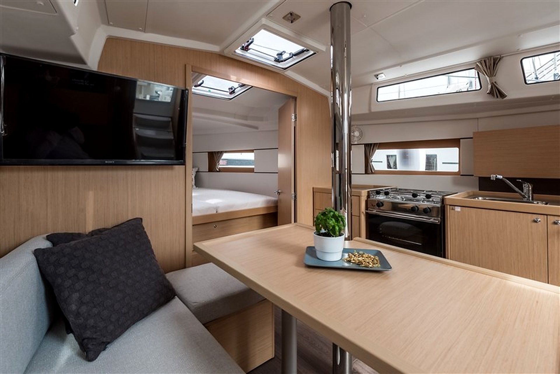 A compact galley with a stove, sink, and a small seating area with a cushion.