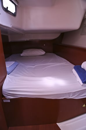 Ein Etagenbett mit weißer Bettwäsche, einem blauen Handtuch und einem Holz-Kopfteil.