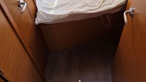 Een compact bed met hoofdbord, een raam met uitzicht en een houten vloer.