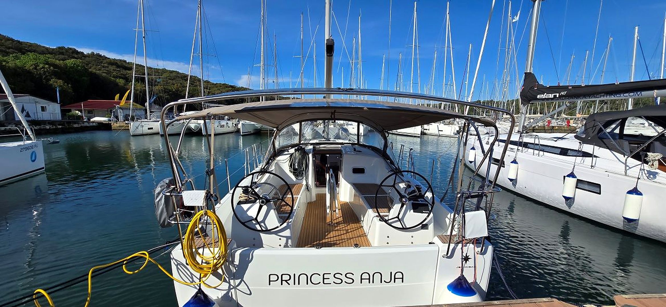 A marina with multiple sailboats docked, a covered walkway, and a boat named 'PRINCESS ANJA' in the foreground.