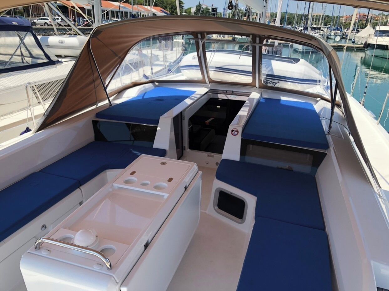 A boat interior with seating, a control panel, and a view of the marina.