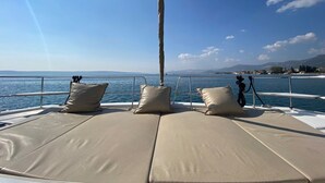 A boat deck with cushioned seating and a railing, overlooking a calm sea and distant land. - Sun-Kissed Sailing Adventure in Split, Croatia (Kaštel Gomilica)