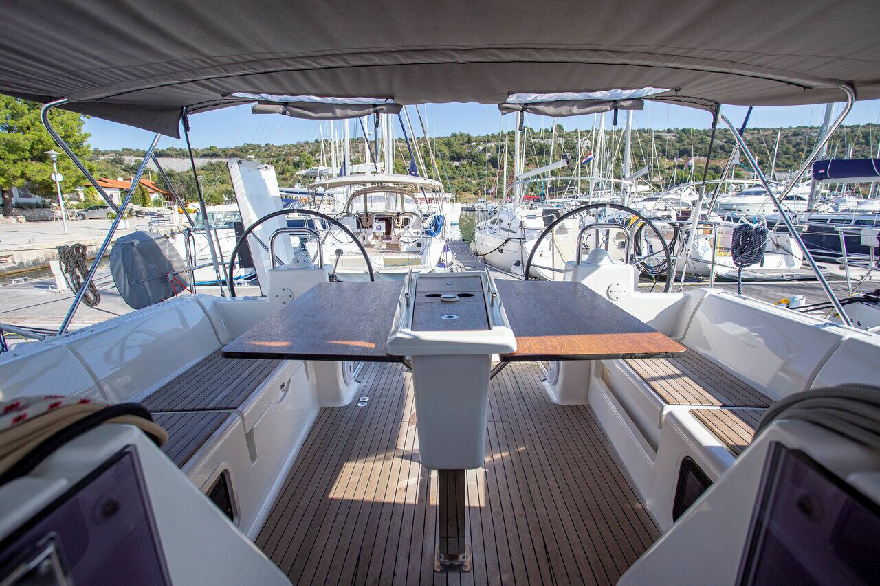 A boat deck with a central table, steering wheel, and multiple chairs.