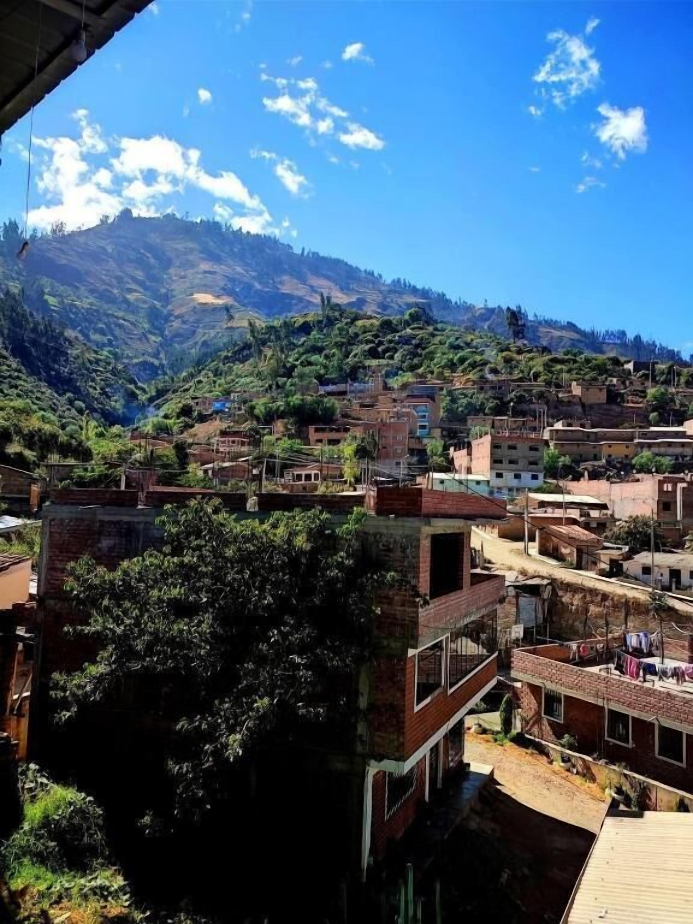 Un pueblo con edificios tradicionales, una montaña al fondo y un cielo despejado.