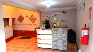 Zona de recepción con mostrador, extintor y señales de salida de emergencia.