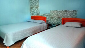 Una habitación con dos camas, cada una con cabecero de madera, pared de piedra y suelo de madera.