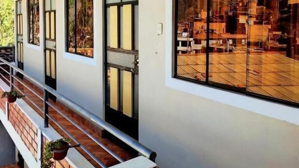 Un edificio con balcón, ventanas amplias y vistas a un paisaje urbano.