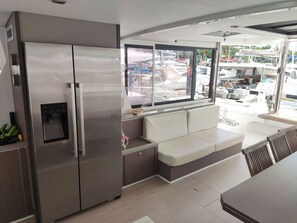 A modern kitchen with a stainless steel refrigerator, a built-in water dispenser, and a seating area with a cushioned bench.