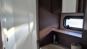 Une salle de bain avec une douche, un lavabo, un miroir et une fenêtre.