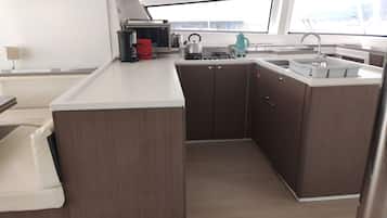 Cocina compacta con una isla central, un lavamanos y un ventanal que proporciona luz natural.
