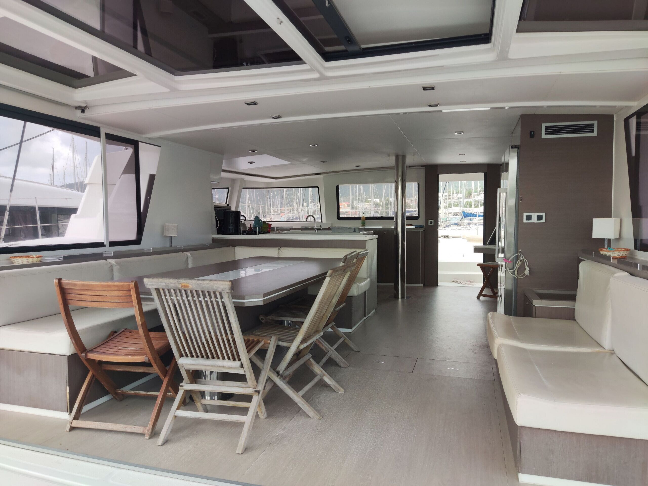 Una cucina moderna con isola centrale, angolo relax con sedie e ampie finestre che offrono vista sul porto turistico.