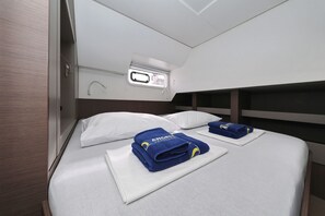 A cabin with bunk beds, a small window, and neatly folded towels. - Sibenik Sun and Beach Sailing Extravaganza: A Croatian Coastal Adventure (Vodice)