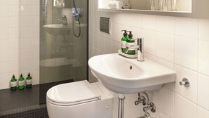 A modern bathroom with a glass-enclosed shower, a white sink, and a toilet. - The Collector's House by Muse (Reykjavík)