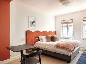 Ein Schlafzimmer mit Bett, Schreibtisch und Fenster.