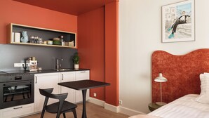A compact room with a kitchenette, a dining area, a bed, and a painting on the wall. - The Collector's House by Muse (Reykjavík)