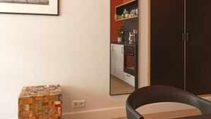 A room with a wooden floor, a dining table with chairs, a wooden cube, a framed picture on the wall, and a kitchen visible through an open door. - The Collector's House by Muse (Reykjavík)