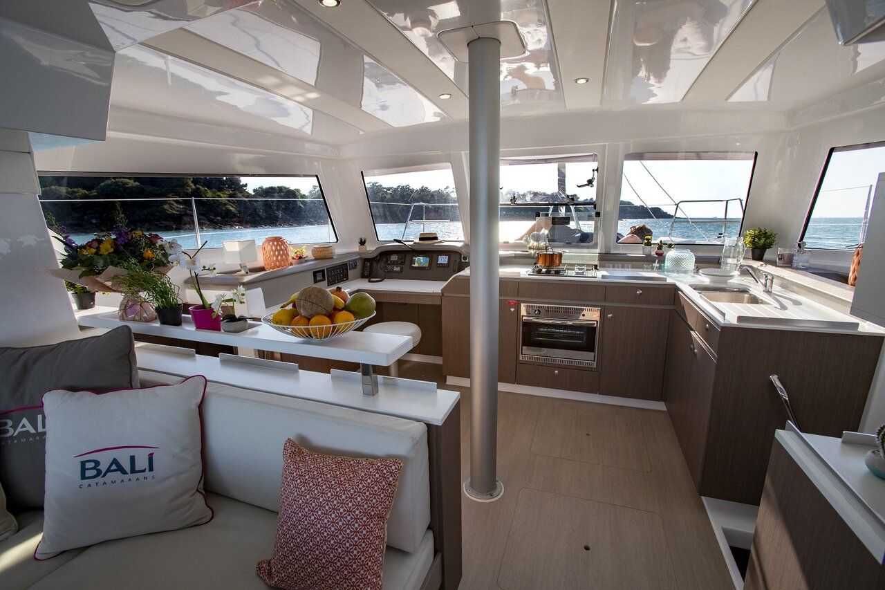 A yacht interior with a dining area, kitchen, and seating with a view of the sea.