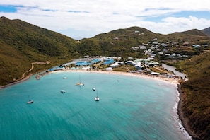 An aerial view of a coastal area with a beach, boats, and buildings.