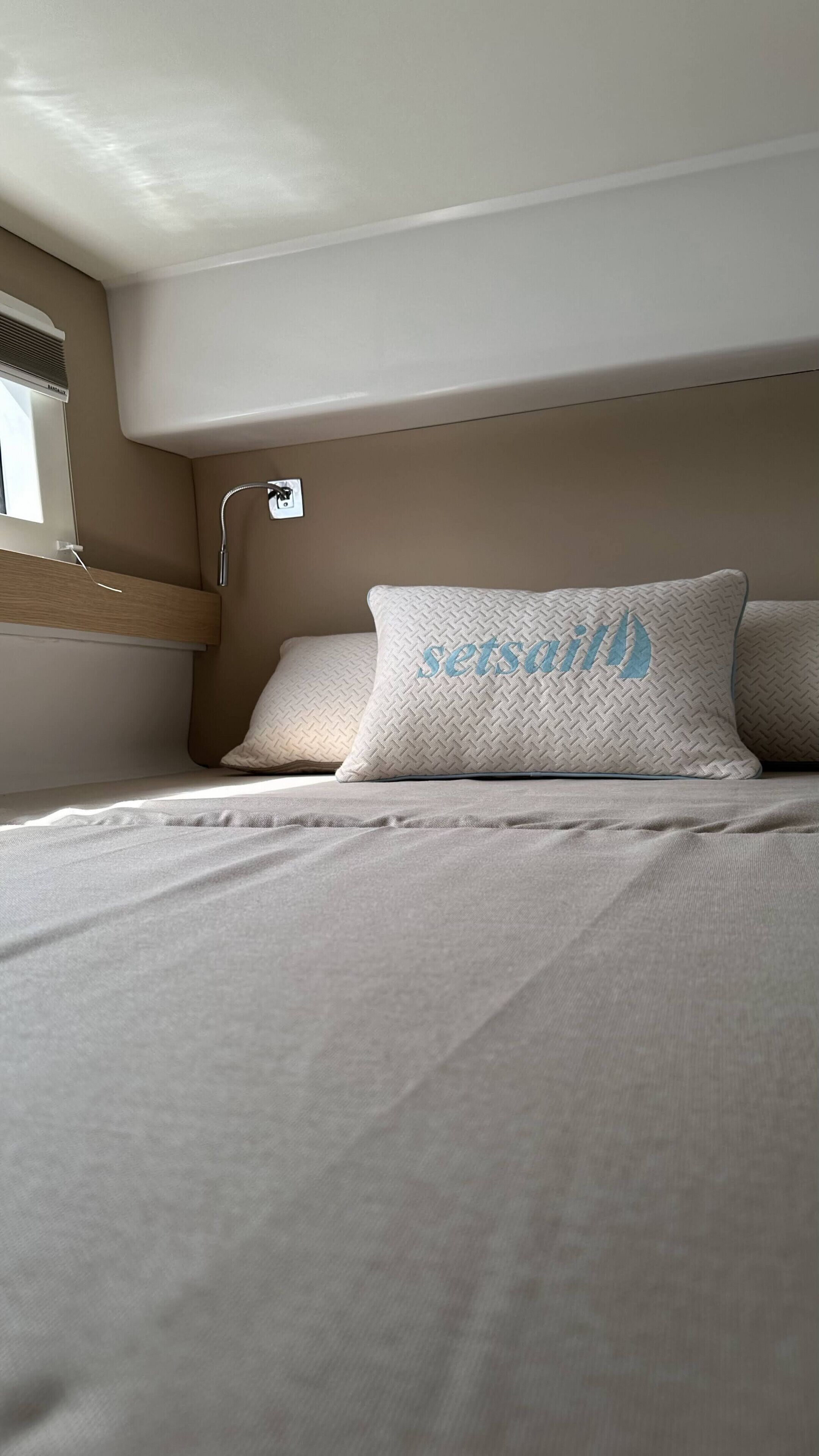 Een stapelbed met hoofdeinde, raam en een douchethermostaat aan de muur.