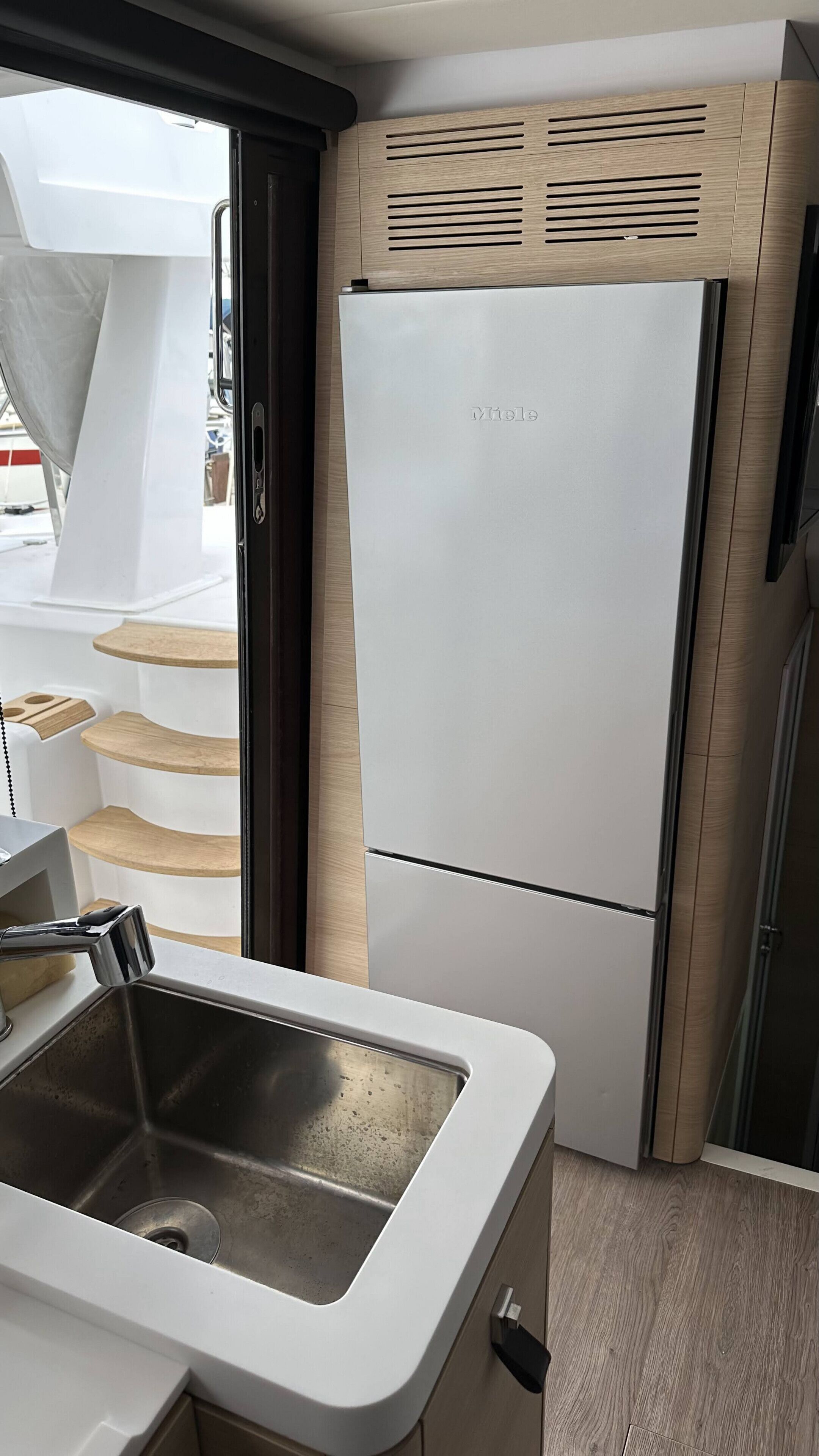 A compact kitchen with a built-in sink, a white refrigerator, and wooden cabinetry.