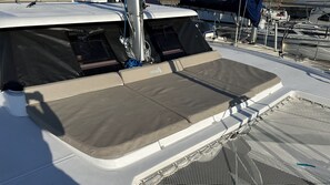 A boat's deck with a covered seating area, a mast, and a netted section.