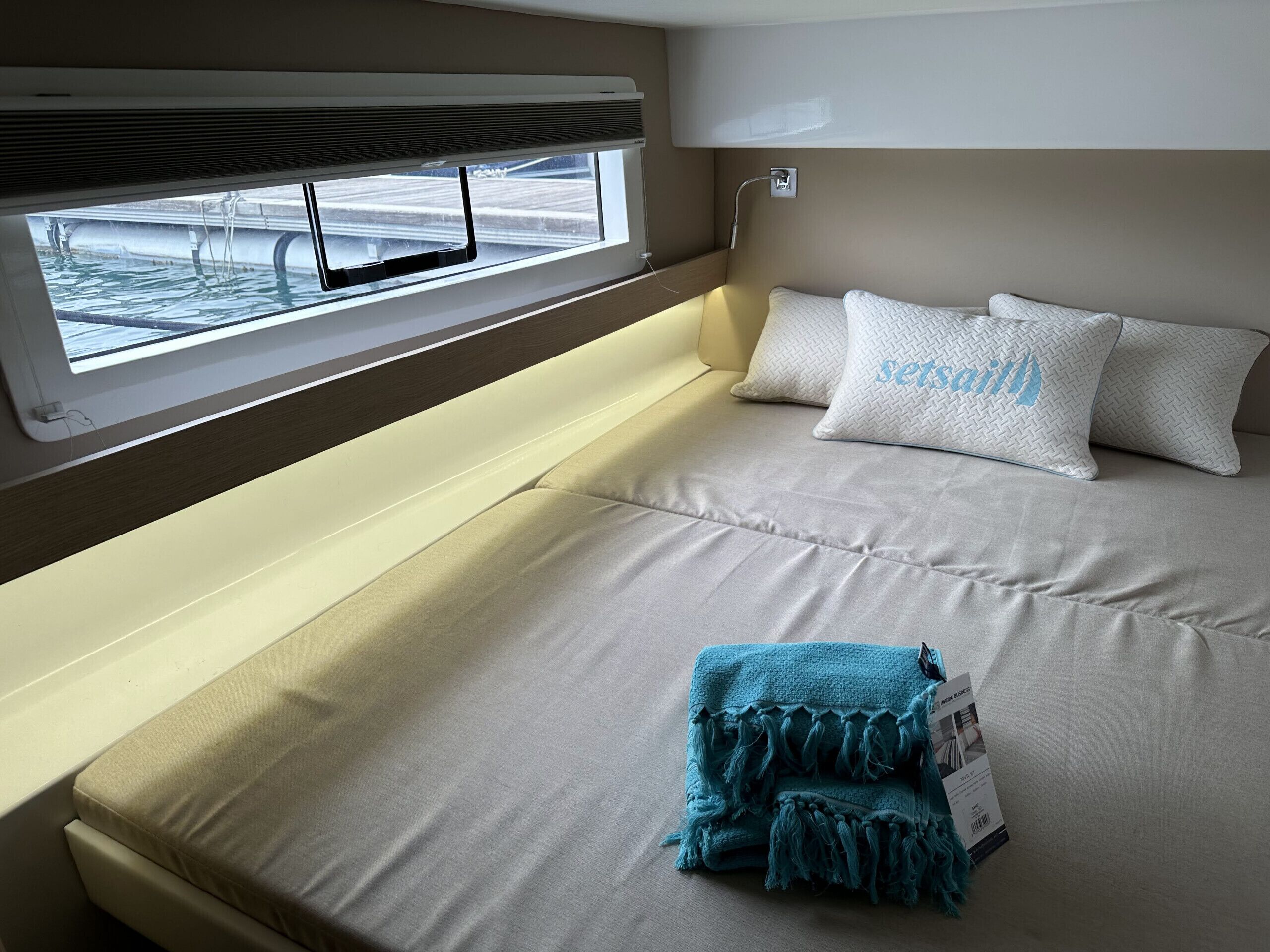 A bed with a window, a headboard, and a blanket.