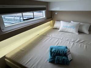 A bed with a window, a headboard, and a blanket. - Sun-Kissed Sailing Adventure in Valencia (Valencia / València)