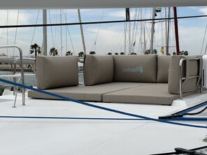 Un pont de bateau doté d’une zone de sièges rembourrés, d’une rambarde en métal et du logo « setsail » apposé sur le coussin.
