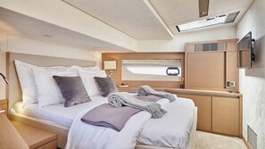 A modern, well-lit bedroom with a bed, bedside tables, a headboard, a window, and a built-in air conditioning unit. - Sun-kissed Sailing Adventure in Split-Dalmatia, Croatia (Trogir)