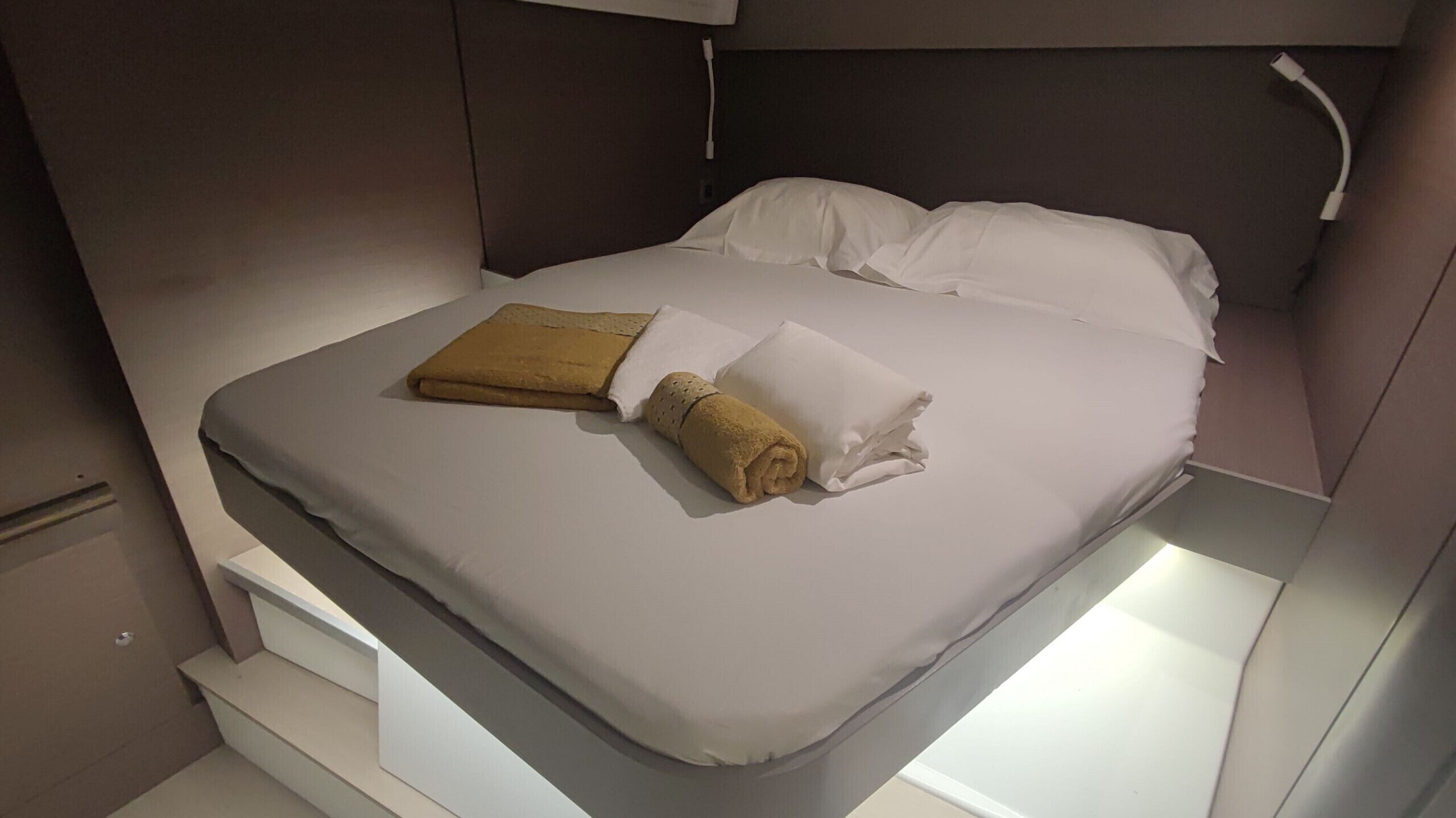 A neatly made bed with a white pillow and a folded towel.