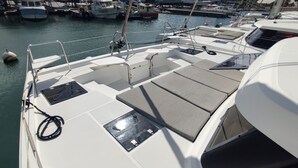 Ein Bootsdeck mit Sitzgelegenheiten, einem Steuer und einem Wasserweg mit weiteren Booten.