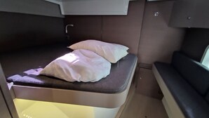 Ein kleiner, privater Schlafbereich mit einem Bett, Kissen und einer Sitzbank.