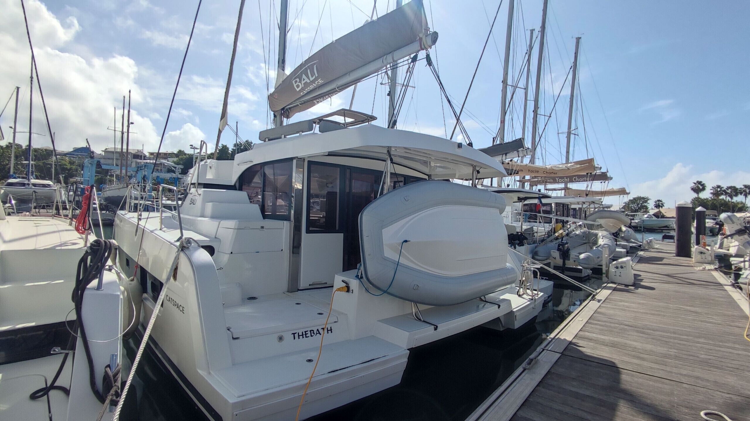 A white yacht docked at a marina with 'BALI' and 'THEBATH' visible on the side.