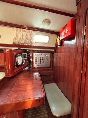 A compact, well-lit cabin with a wooden bench, a control panel, and a red emergency kit. - Sun-Kissed Sailing Adventure in Islas Sarónicas (Alimos)