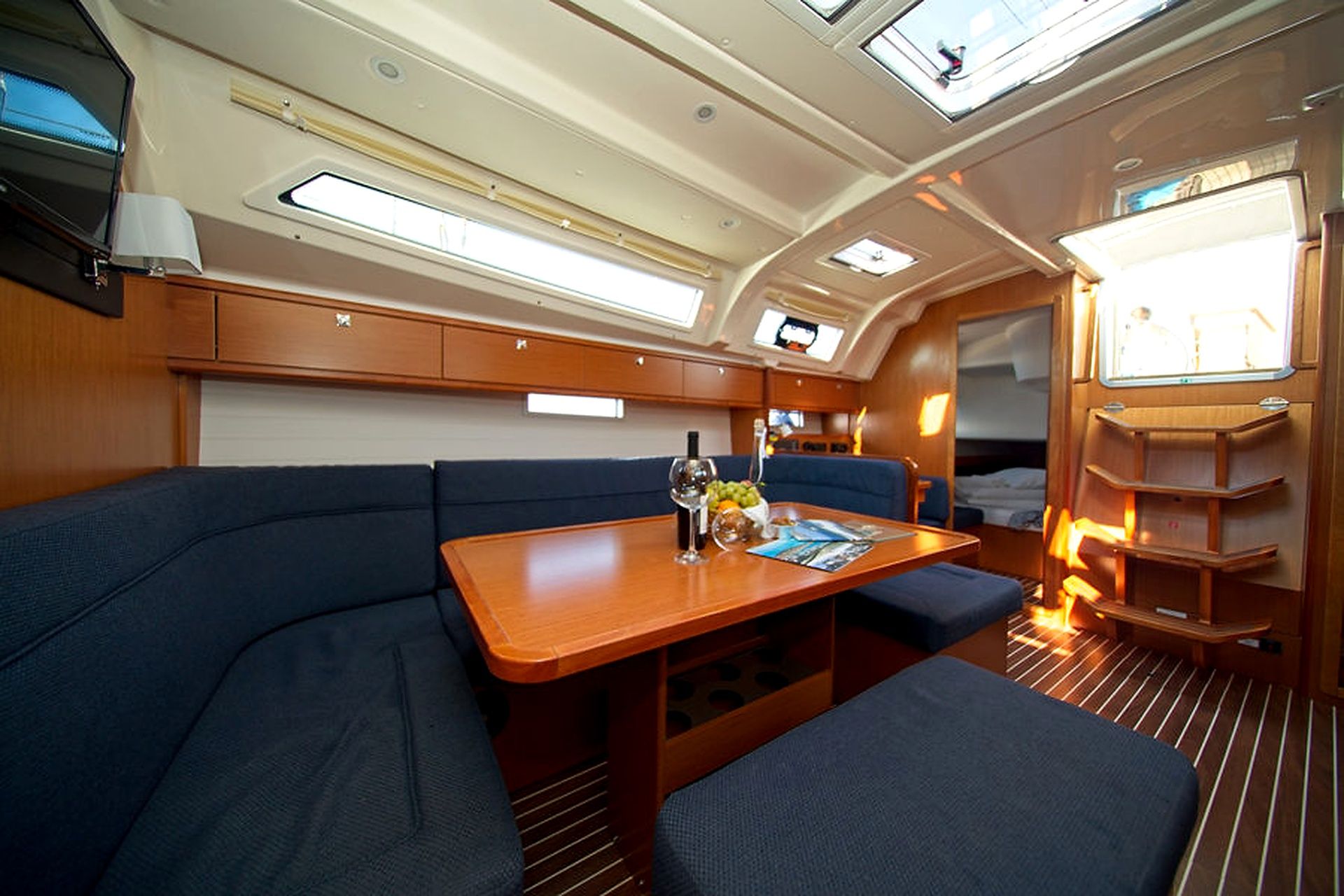 Espacio interior compacto con comedor, asientos acolchados y una pequeña mesa con una botella y copas.