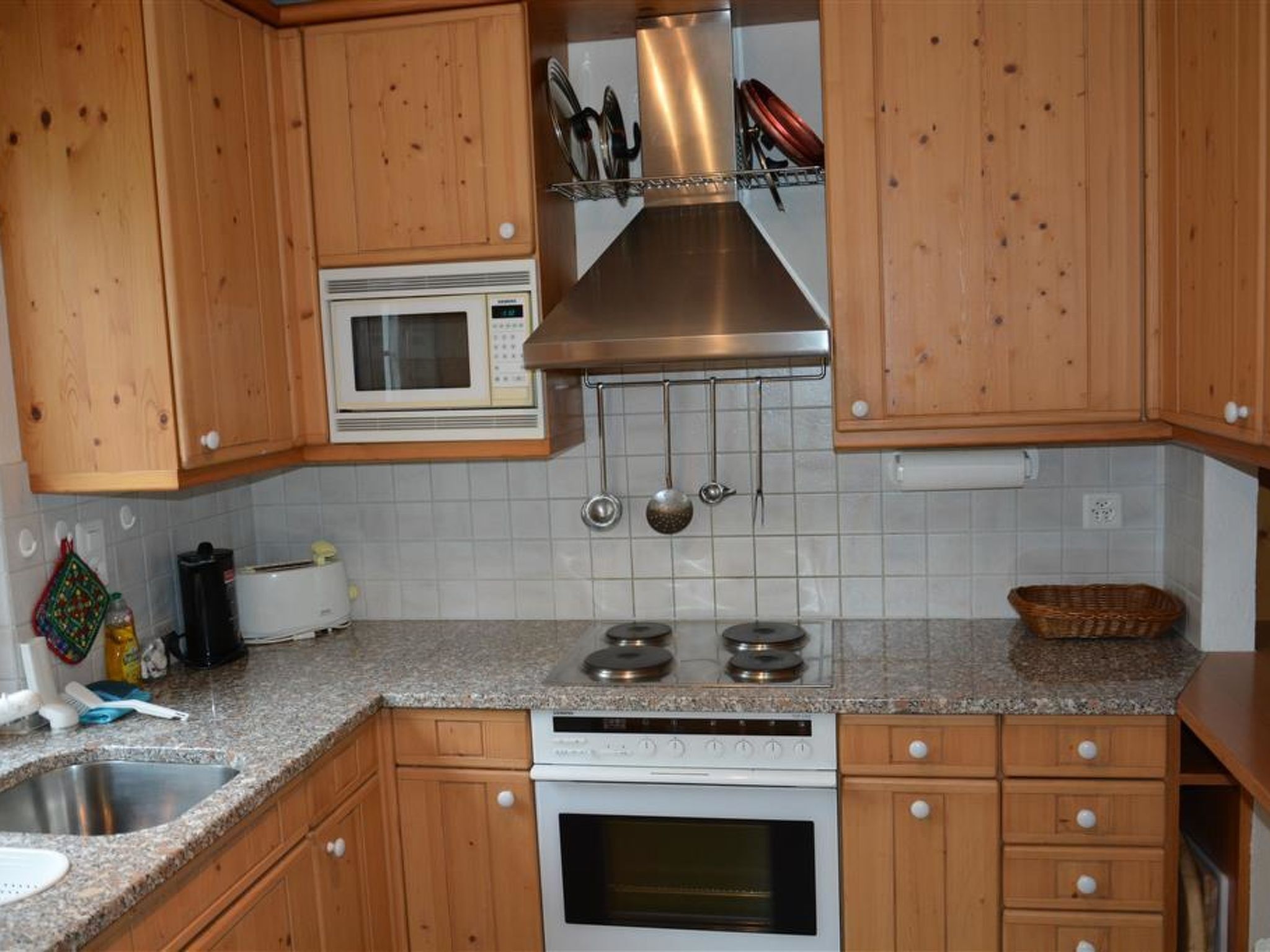 A kitchen with wooden cabinets, a microwave, a stove, and a sink.